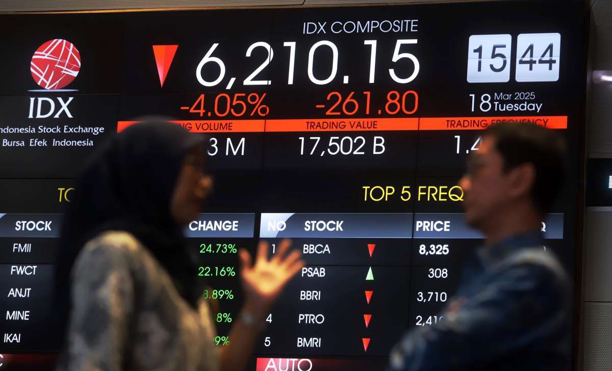Dua orang karyawan sedang berbica di depan monitor tampilan IHSG