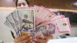 Petugas menunjukkan uang pecahan dolar AS dan rupiah di gerai penukaran mata uang asing, Jakarta
