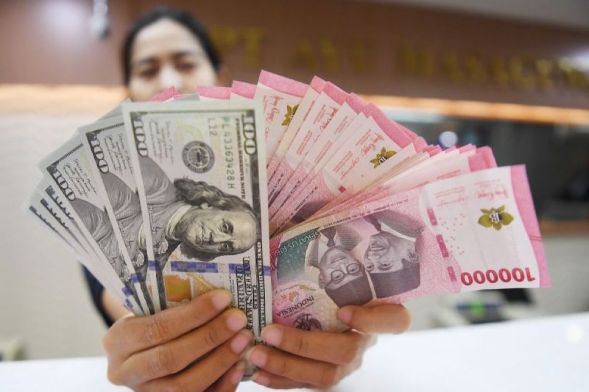Petugas menunjukkan uang pecahan dolar AS dan rupiah di gerai penukaran mata uang asing, Jakarta