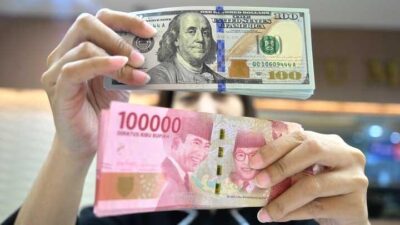 Ilustrasi- seseorang sedang memegang uang pecahan seratus ribu rupiah dan dollar USA